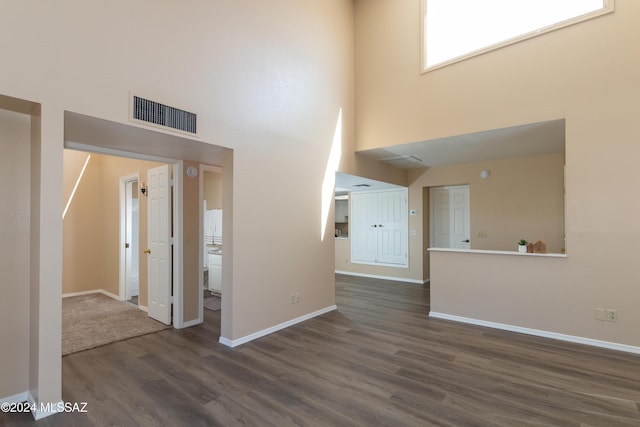 entrance foyer with dark wood-style floors, visible vents, a high ceiling, and baseboards