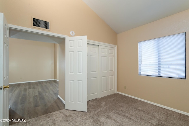 unfurnished bedroom with visible vents, a closet, carpet flooring, baseboards, and vaulted ceiling