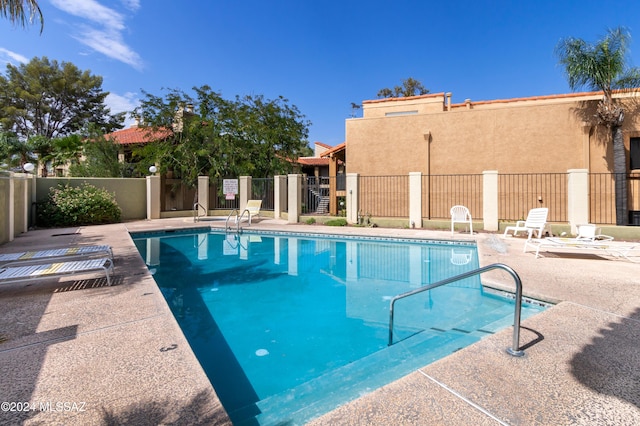 community pool with a patio area and fence