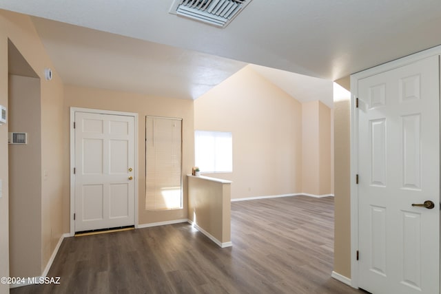 interior space with visible vents, baseboards, wood finished floors, and vaulted ceiling