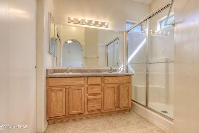 full bath with double vanity, a stall shower, and a sink