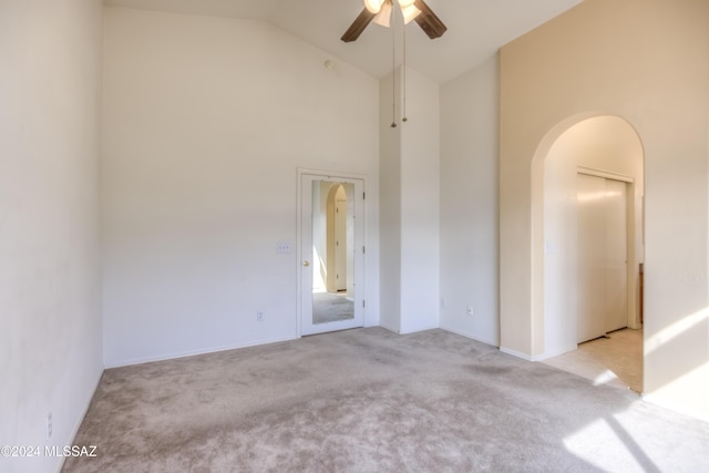 spare room featuring arched walkways, high vaulted ceiling, carpet flooring, and a ceiling fan