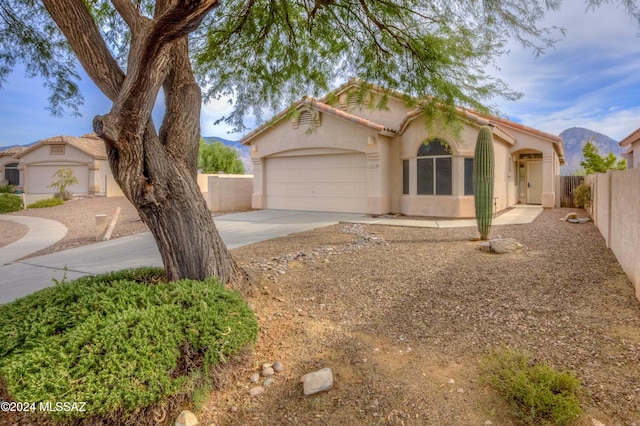 view of front facade featuring driveway, a tile roof, an attached garage, fence, and stucco siding