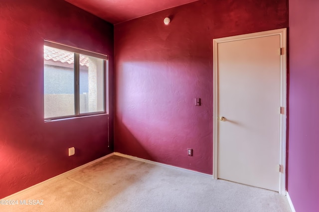 unfurnished room with carpet, baseboards, and a textured wall