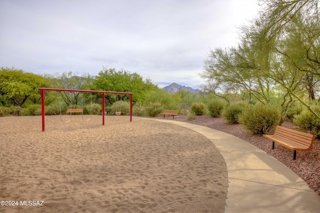 surrounding community with playground community and a mountain view