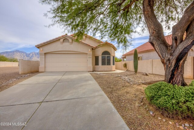 view of front of house with concrete driveway, fence, an attached garage, and stucco siding