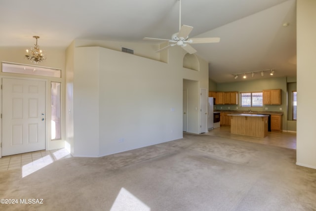 unfurnished living room with light carpet, high vaulted ceiling, visible vents, and ceiling fan with notable chandelier