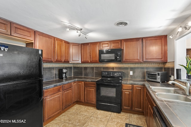 kitchen with sink, black appliances, backsplash, and light tile patterned floors