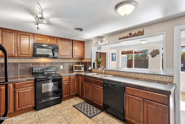 kitchen with light tile patterned flooring, decorative backsplash, black appliances, and sink