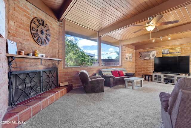 carpeted living room featuring wood ceiling, a tiled fireplace, ceiling fan, beamed ceiling, and brick wall