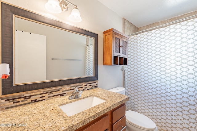 bathroom with vanity, tasteful backsplash, toilet, and walk in shower