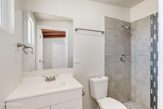 full bath featuring vanity, a tile shower, and toilet