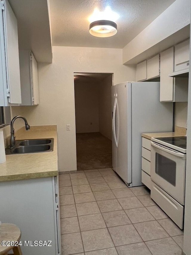 kitchen with sink, white appliances, light tile patterned floors, and white cabinets