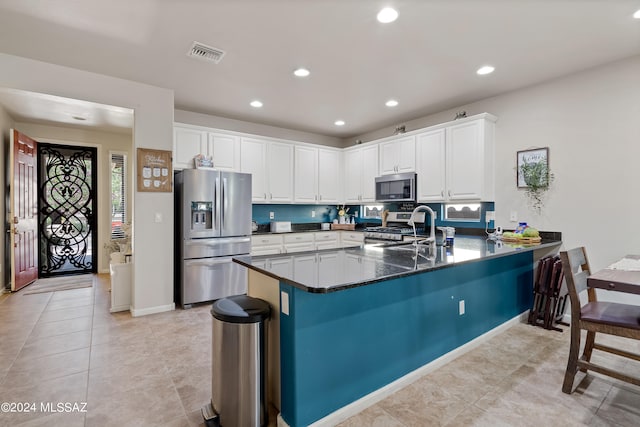 kitchen featuring kitchen peninsula, light tile patterned floors, stainless steel appliances, and white cabinetry