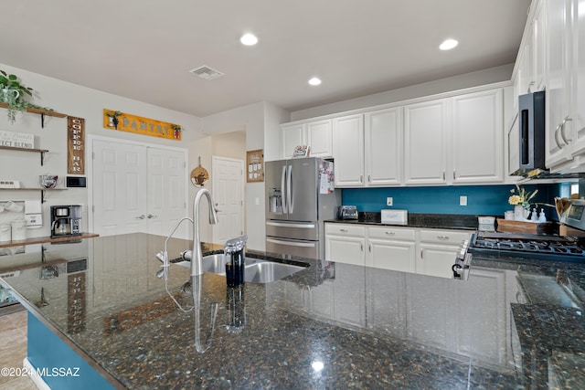 kitchen with white cabinets, sink, stainless steel appliances, and dark stone counters