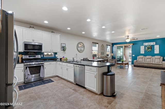 kitchen featuring kitchen peninsula, stainless steel appliances, ceiling fan, sink, and white cabinets