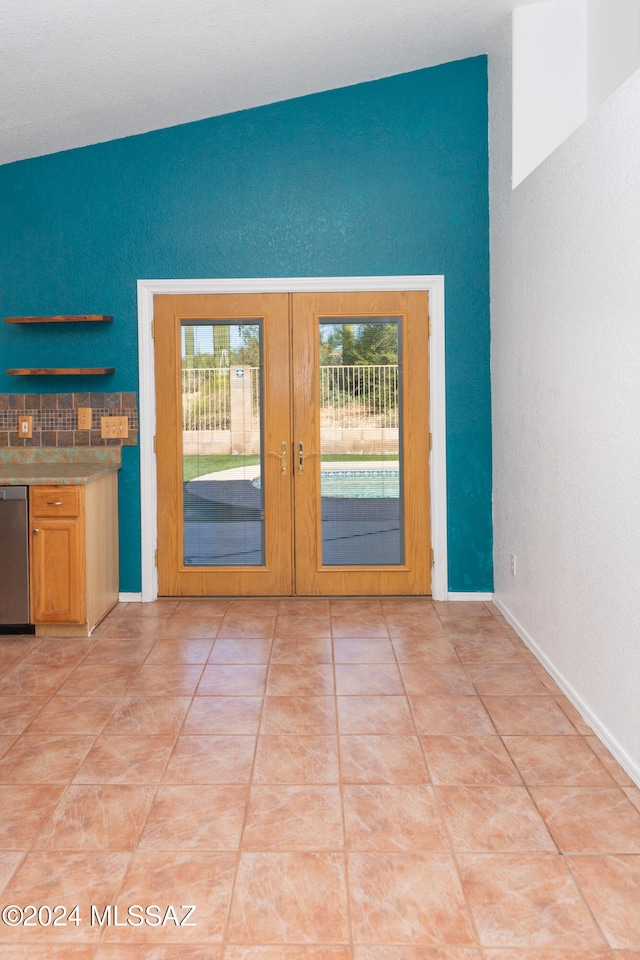 doorway to outside with french doors, light tile patterned floors, and vaulted ceiling