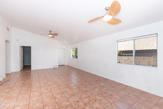 tiled spare room with a healthy amount of sunlight, ceiling fan, and vaulted ceiling