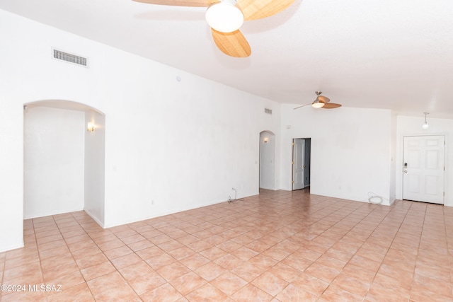 spare room featuring a towering ceiling, light tile patterned flooring, and ceiling fan