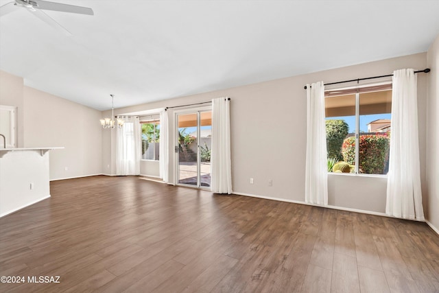 empty room with dark hardwood / wood-style flooring, ceiling fan with notable chandelier, and sink