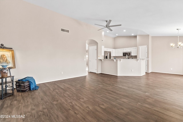 unfurnished living room with ceiling fan with notable chandelier, dark hardwood / wood-style floors, and high vaulted ceiling