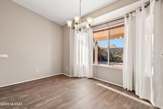 unfurnished room with hardwood / wood-style flooring and an inviting chandelier