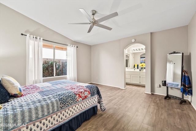 bedroom with wood-type flooring, connected bathroom, vaulted ceiling, and ceiling fan