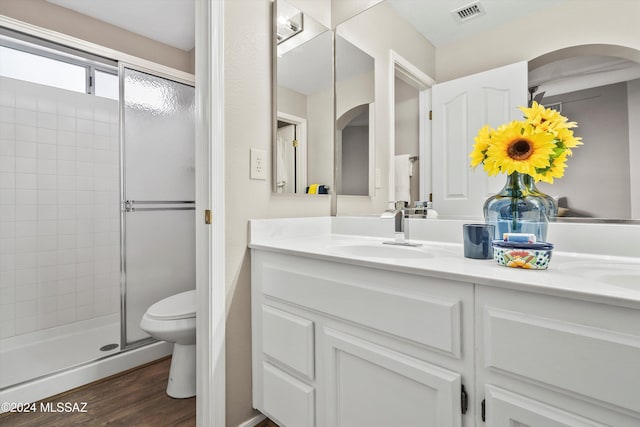 bathroom featuring wood-type flooring, vanity, toilet, and a shower with door