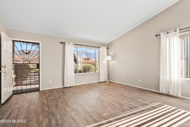 unfurnished room featuring wood-type flooring and vaulted ceiling