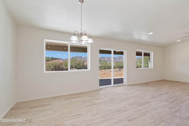 unfurnished room featuring light wood-type flooring and an inviting chandelier