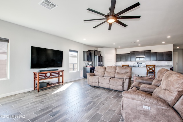 living room featuring sink, light hardwood / wood-style floors, and ceiling fan