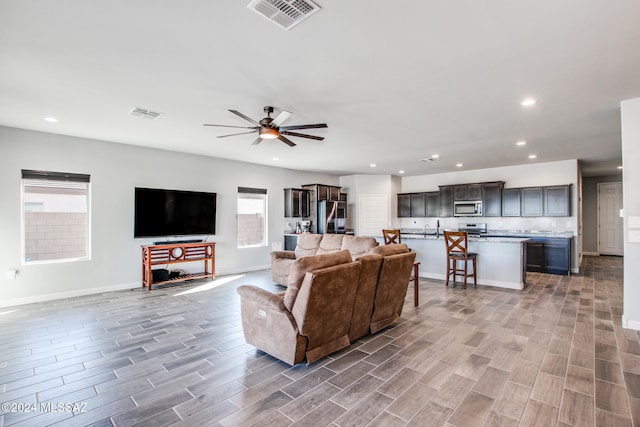 living room with light hardwood / wood-style flooring, ceiling fan, sink, and a wealth of natural light