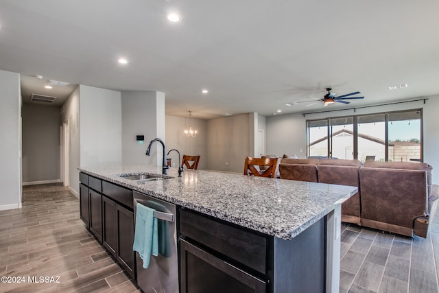 kitchen featuring wood-type flooring, sink, an island with sink, stainless steel dishwasher, and light stone counters