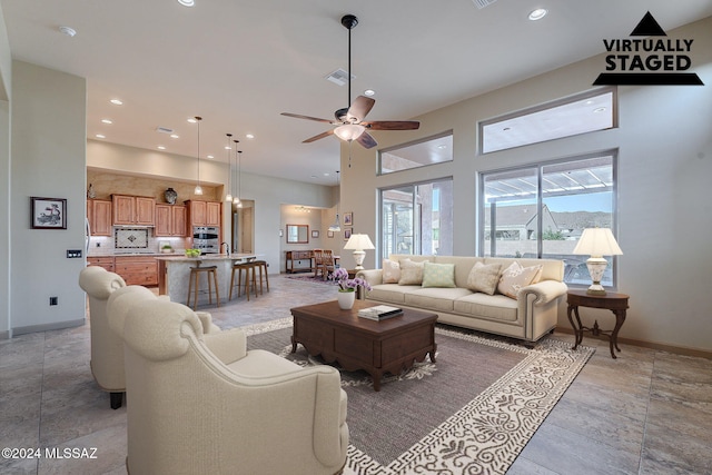 living room featuring ceiling fan and a towering ceiling