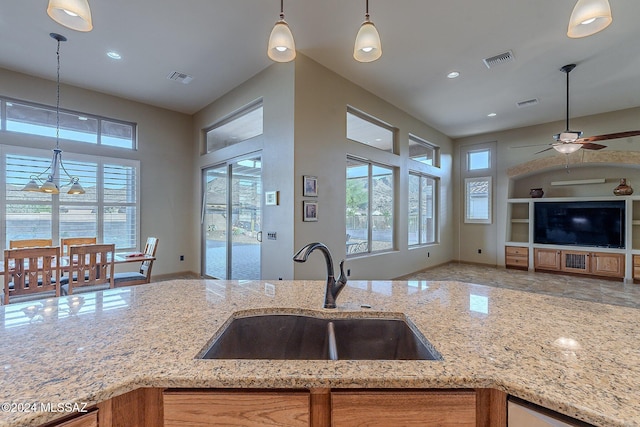 kitchen featuring light stone countertops, sink, and pendant lighting