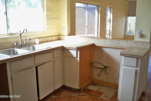 kitchen featuring a wealth of natural light, sink, kitchen peninsula, and tile countertops