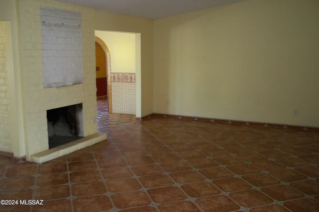 unfurnished living room with dark tile patterned floors and a fireplace