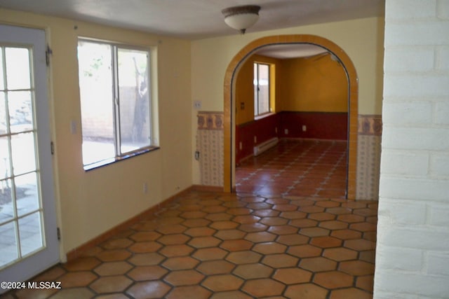 interior space with a healthy amount of sunlight, a baseboard heating unit, and dark tile patterned floors