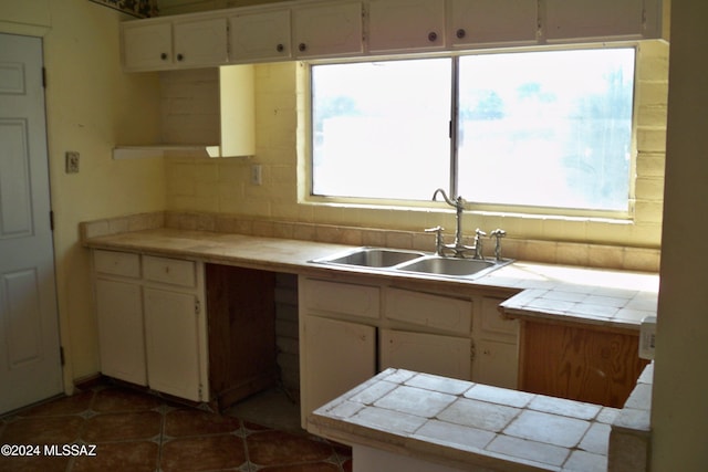 kitchen with tile countertops, tasteful backsplash, sink, and dark tile patterned flooring