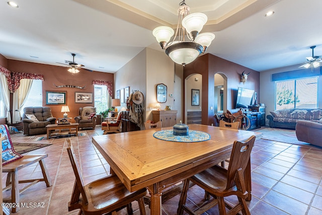 tiled dining room with ceiling fan with notable chandelier and a wealth of natural light