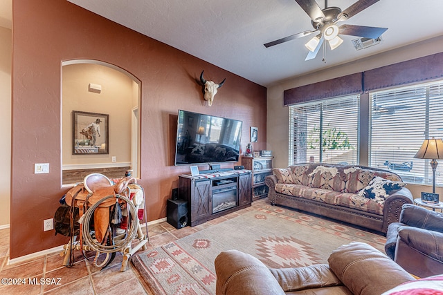 living room featuring a textured ceiling, light tile patterned floors, and ceiling fan