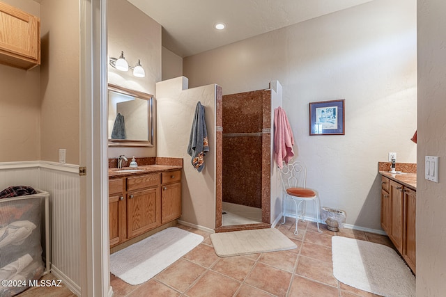 bathroom with vanity, tiled shower, and tile patterned flooring