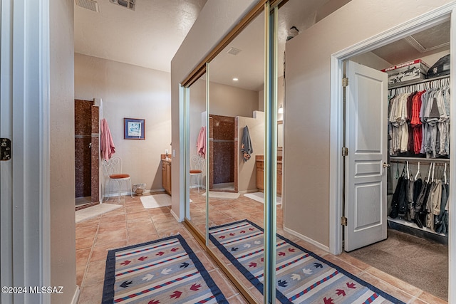 bathroom featuring a shower with door, vanity, and tile patterned flooring