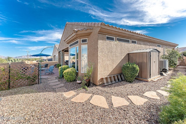 view of property exterior with central AC unit, a patio area, and a shed