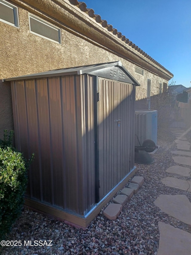 view of side of home featuring a storage shed and central AC