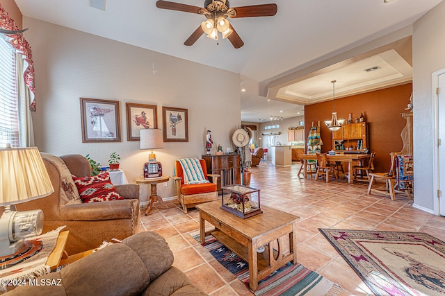 living room featuring ceiling fan, plenty of natural light, light tile patterned floors, and a tray ceiling