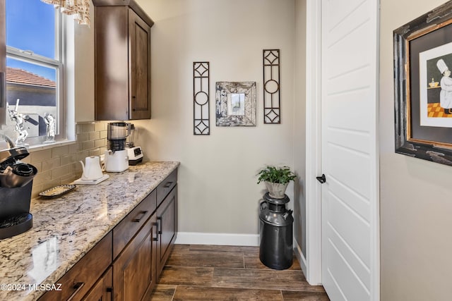 bar with dark brown cabinetry, light stone countertops, and tasteful backsplash