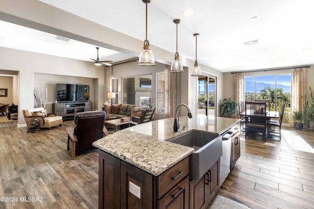 kitchen with light stone counters, ceiling fan, sink, dishwasher, and dark hardwood / wood-style floors