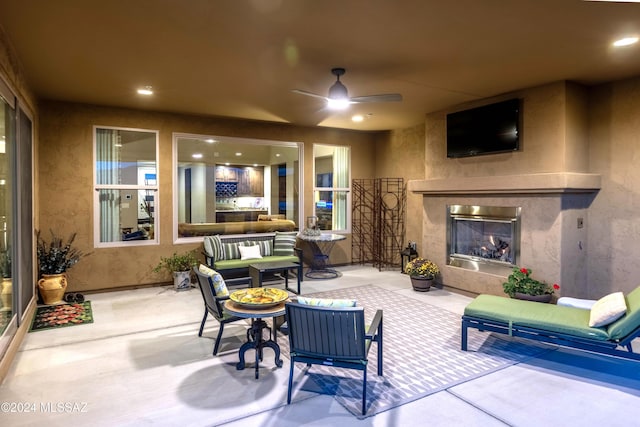 view of patio with an outdoor living space with a fireplace and ceiling fan