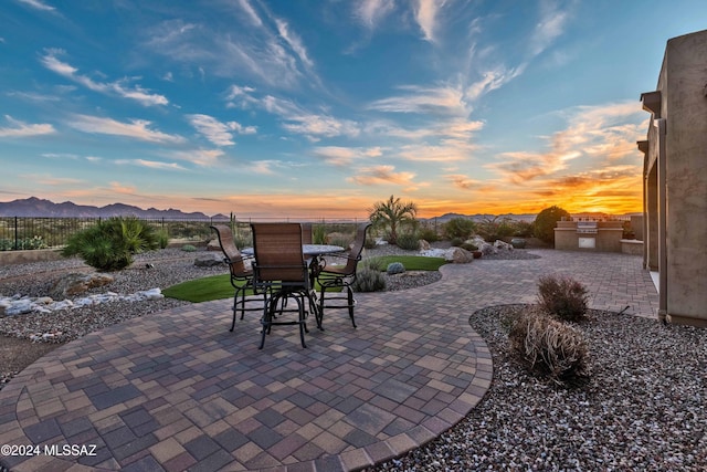 patio terrace at dusk featuring a mountain view and exterior kitchen